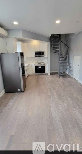 A spacious kitchen with a refrigerator and a staircase.