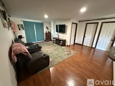 A living room with a black couch and a rug.