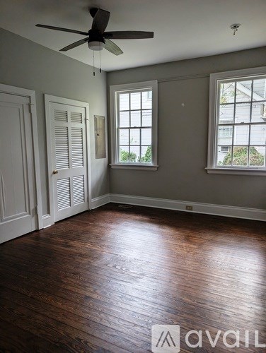 A room with a ceiling fan and two windows.