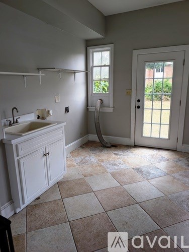 A bathroom with a sink, a window, and a door.