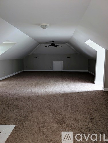 A room with a carpeted floor and a ceiling fan.