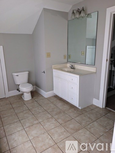 A bathroom with a toilet, sink, and mirror.
