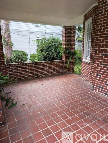 A red brick patio with a white door and window.