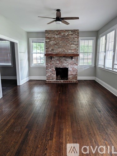 A room with a brick fireplace and wooden floors.