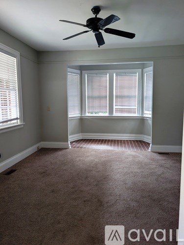 A room with a carpeted floor, a ceiling fan, and a window with blinds.