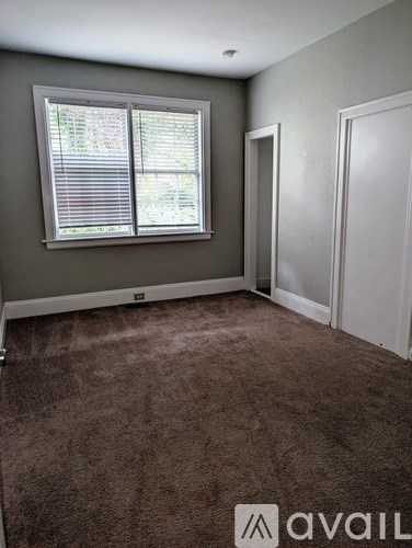 A room with a window and a carpeted floor.
