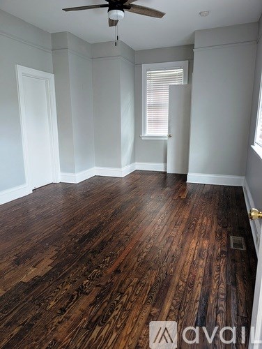 A room with wooden flooring and a ceiling fan.