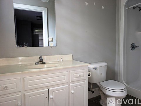 A white bathroom with a sink, toilet, and mirror.