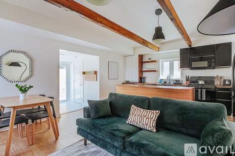 A living room with a green couch and a wooden dining table.