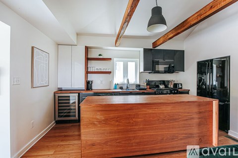 A kitchen with a wooden counter top and black appliances.