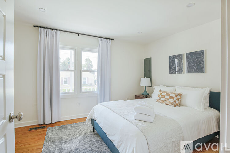 A bedroom with a large bed and a window with curtains.