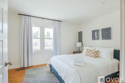 A bedroom with a large bed and a window with curtains.