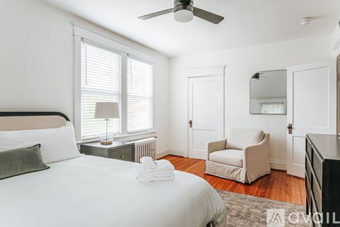 A bedroom with a large bed, a chair, and a ceiling fan.