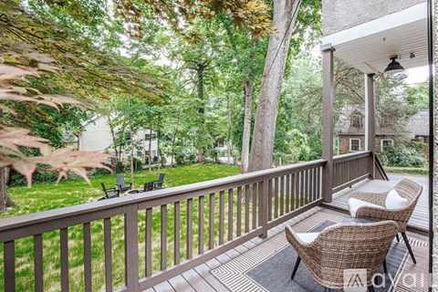 A patio with a table and chairs overlooking a green lawn.