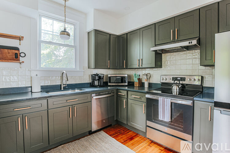 A kitchen with dark green cabinets and stainless steel appliances.