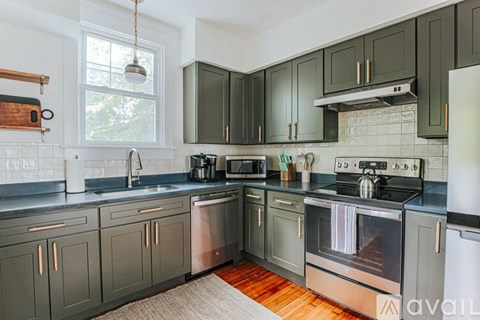 A kitchen with dark green cabinets and stainless steel appliances.