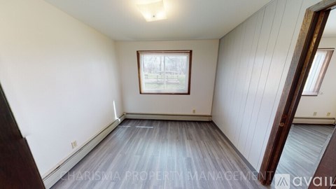 A room with wooden flooring and a window with a view of a building.
