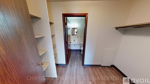 A hallway with a wooden floor and a mirror on the wall.