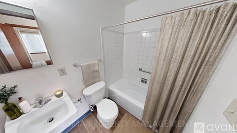 A white bathroom with a toilet, sink, and bathtub.