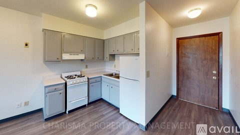 A kitchen with white cabinets and a wooden door.