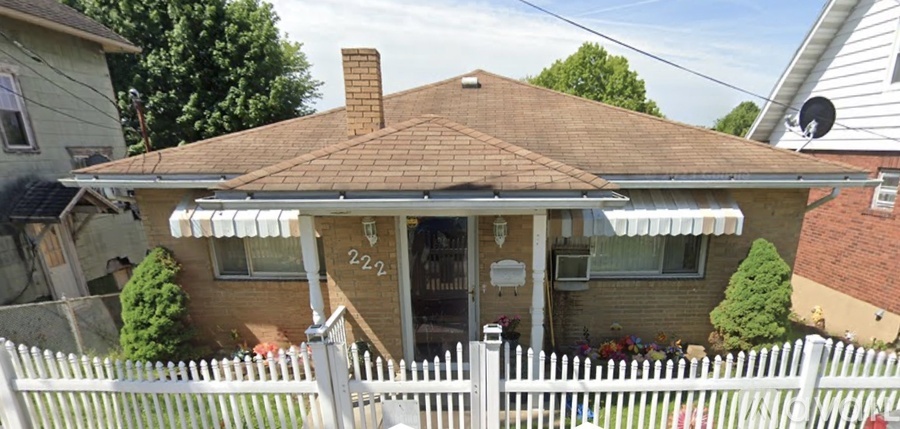 A house with a brown roof and a white picket fence.