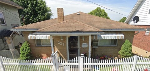 A house with a brown roof and a white picket fence.