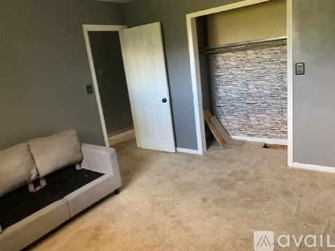 A room with a white door, a grey wall, and a stone wall.