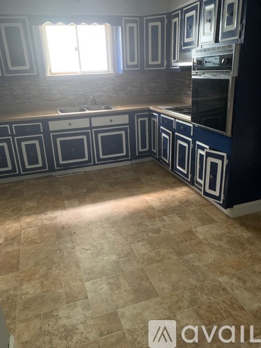 A kitchen with blue and white cabinets and a stone backsplash.