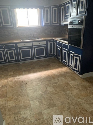A kitchen with blue and white cabinets and a stone backsplash.