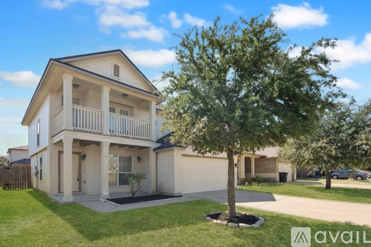 A tree in a flower bed is in front of a house.