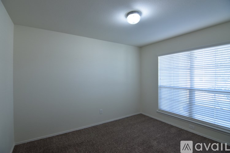 A room with a carpeted floor and a window with blinds.