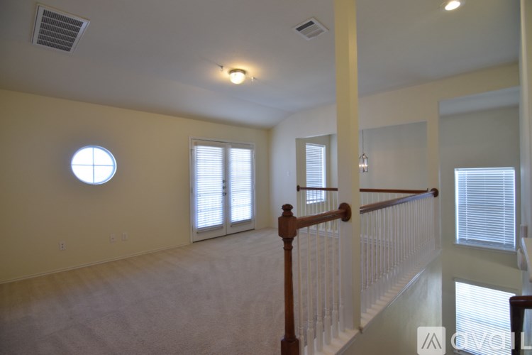 A room with a round window and a wooden staircase.