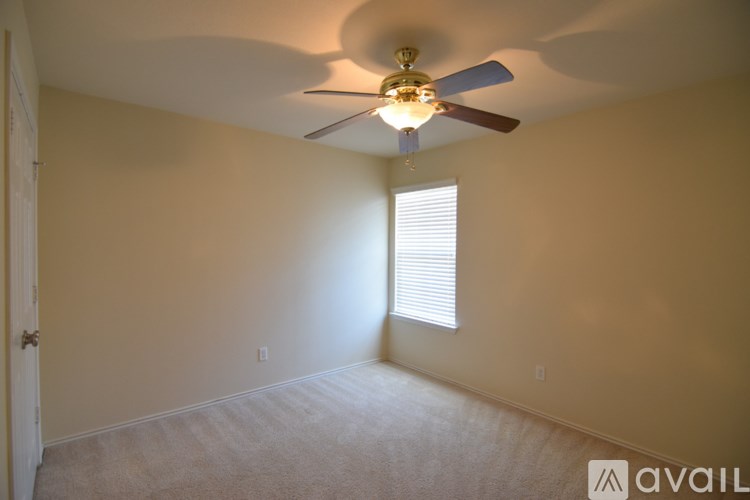 A room with a ceiling fan and a window with blinds.