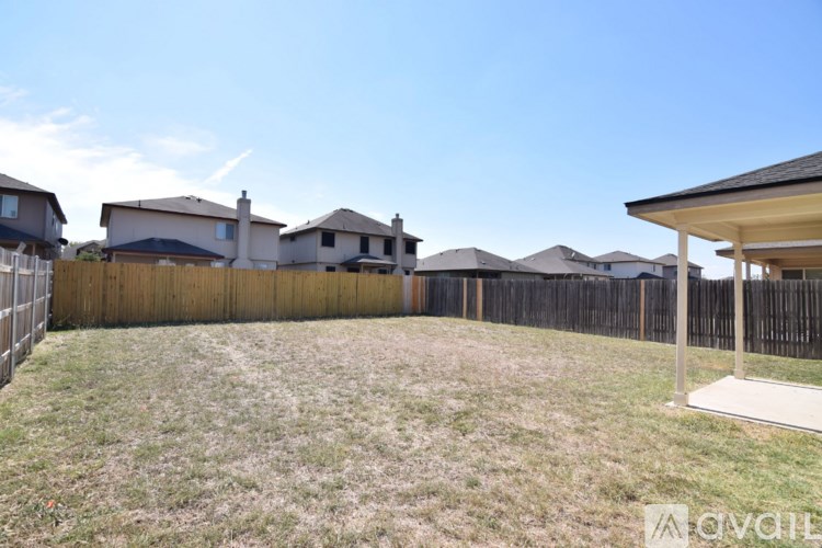 A backyard with a wooden fence and a house in the background.