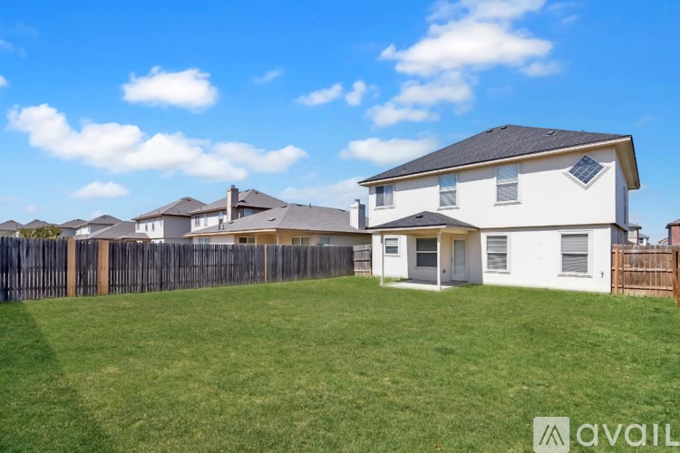 A white house with a black roof and a fence in front of it.