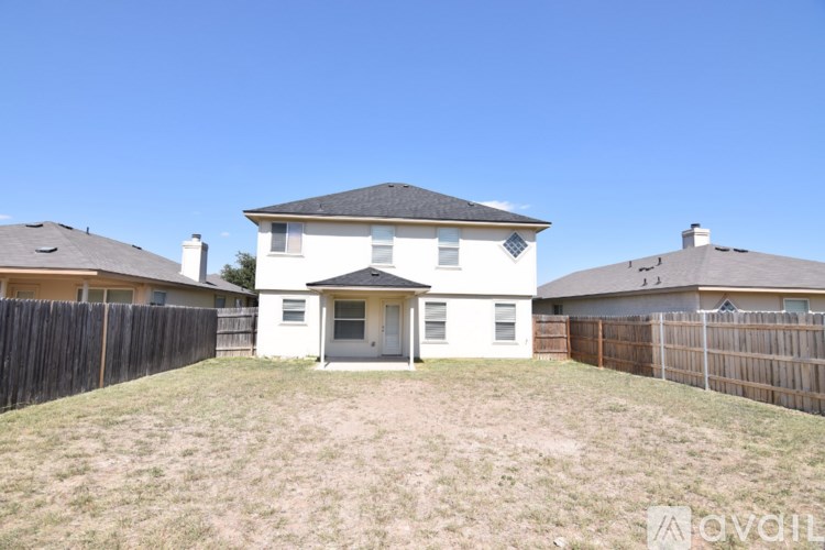 A white house with a black roof is surrounded by a wooden fence.
