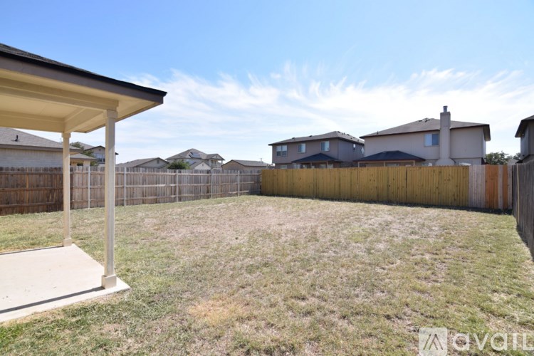 A backyard with a wooden fence and a covered patio area.