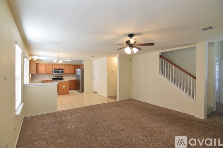 A spacious living room with a brown carpet and a ceiling fan.