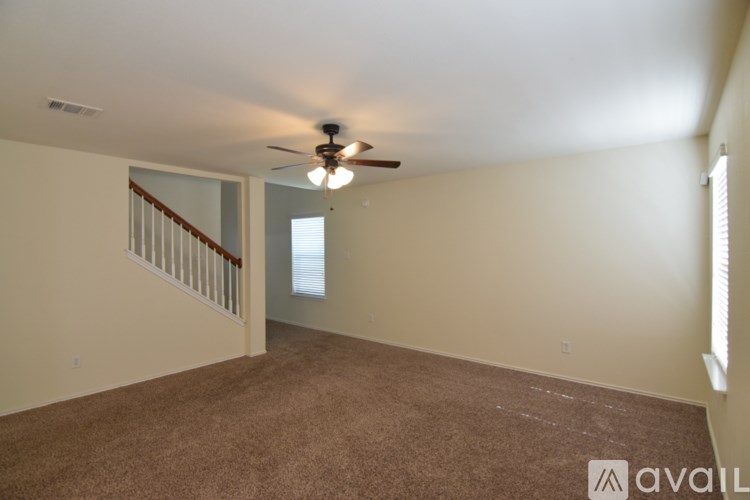 A spacious room with a ceiling fan and carpeted floor.