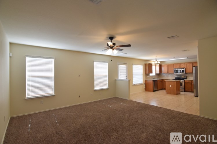 A spacious living room with a carpeted floor and a ceiling fan.