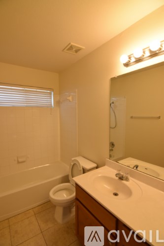 A bathroom with a toilet, sink, and mirror.