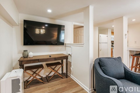 A living room with a television, a desk, and a chair.