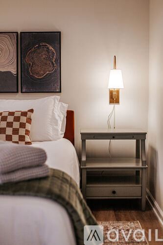 A bedroom with a bed, nightstand, and two wall art pieces.