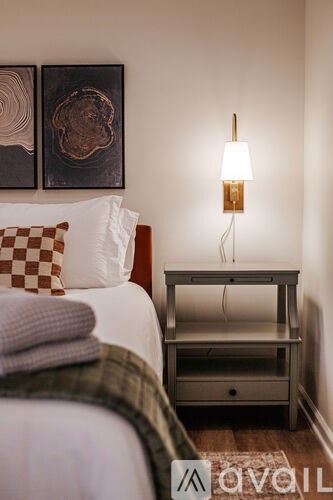 A bedroom with a bed, nightstand, and two wall art pieces.