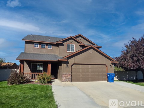 A house with a brown garage door and a blue trash bin in front.