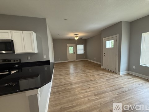 A spacious kitchen with wooden floors and white cabinets.
