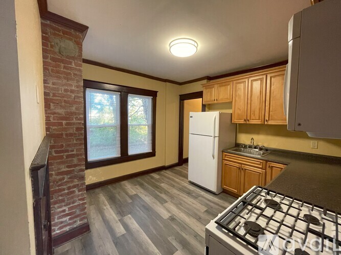 A kitchen with a white fridge and a window with blinds.