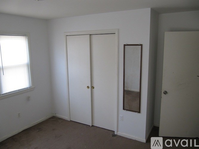 A room with a white door and a window with blinds.