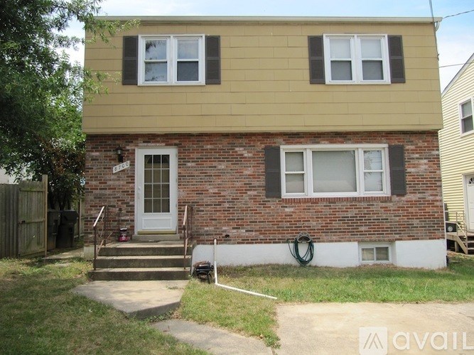 A two-story house with a brick base and a yellow top floor.