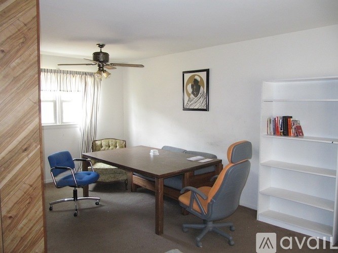 A room with a table, chairs and a bookshelf.